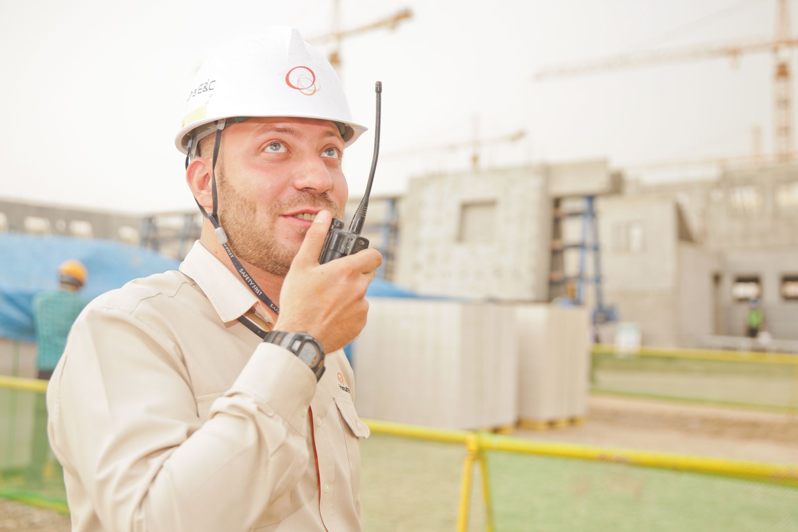 A site worker in a hard hat speaking into a handheld radio, mid-job.